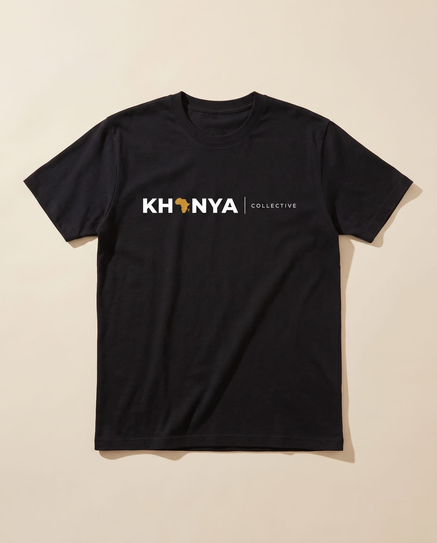 Black T-shirt with a white and ochre Khanya Collective chest print, laid flat on a sand backdrop