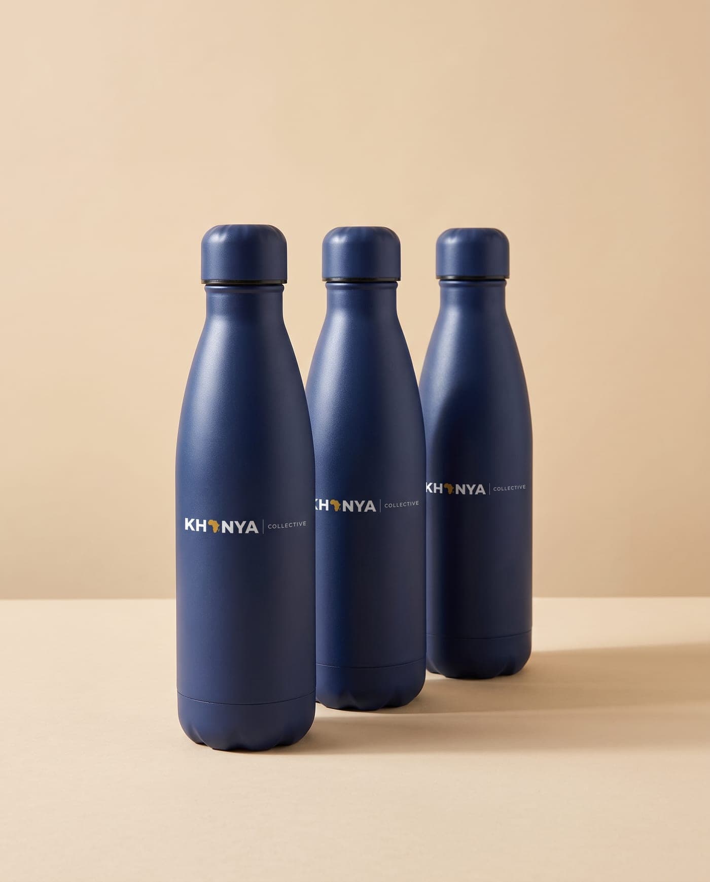 Three navy water bottles printed with the Khanya Collective logo