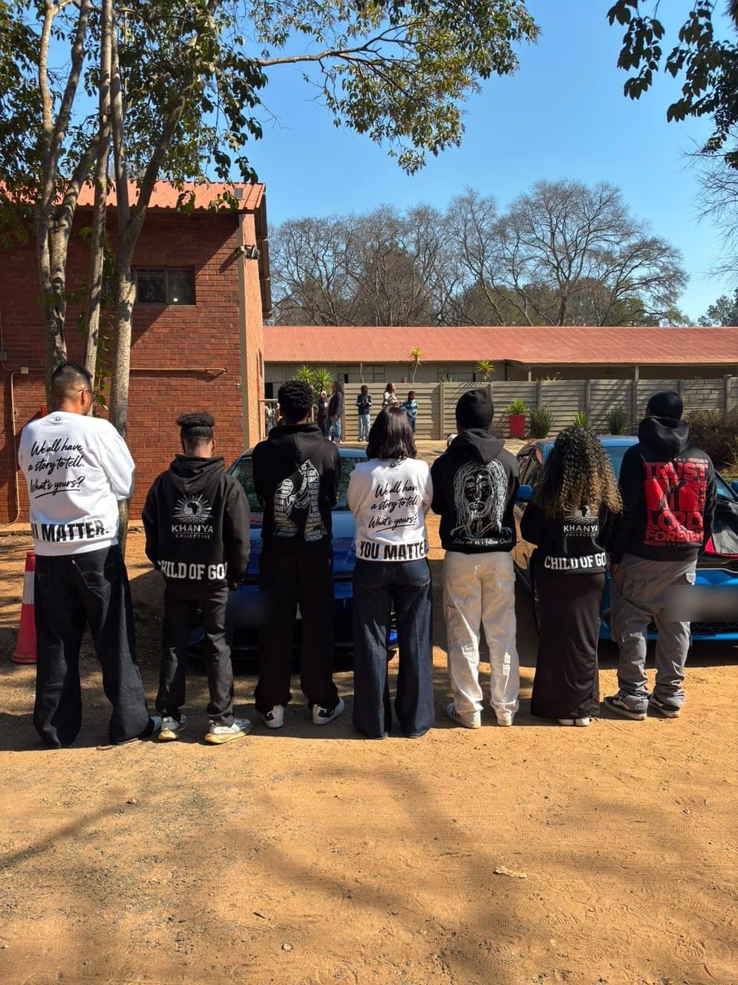 Eight people photographed from behind wearing Khanya Collective hoodies and crewnecks